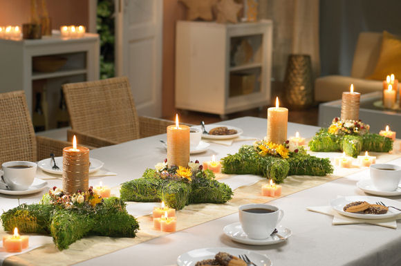 Tannenkränze in Sternform erhellen hier mit goldenen Stumpen und Sternkerzen mit dem RAL-Gütezeichen  die festliche Tafel, die mit weißem Geschirr eingedeckt wurde.